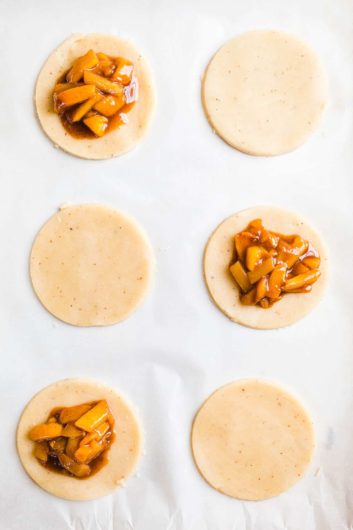 Pie dough rounds with cooked peach on top.