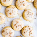 Soft pumpkin cookies with icing on a piece of parchment paper.