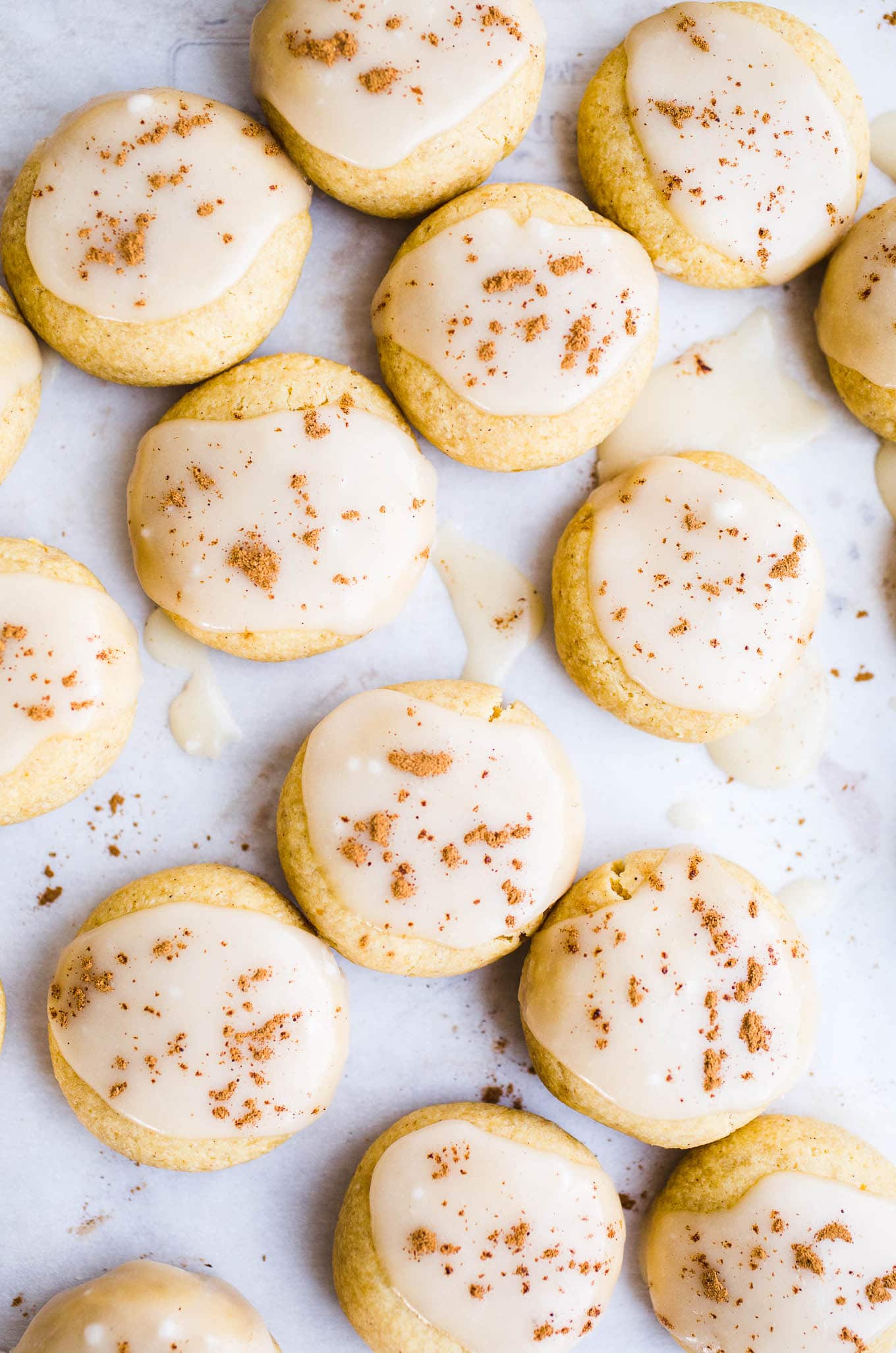 Soft cookies with icing on a piece of parchment paper.