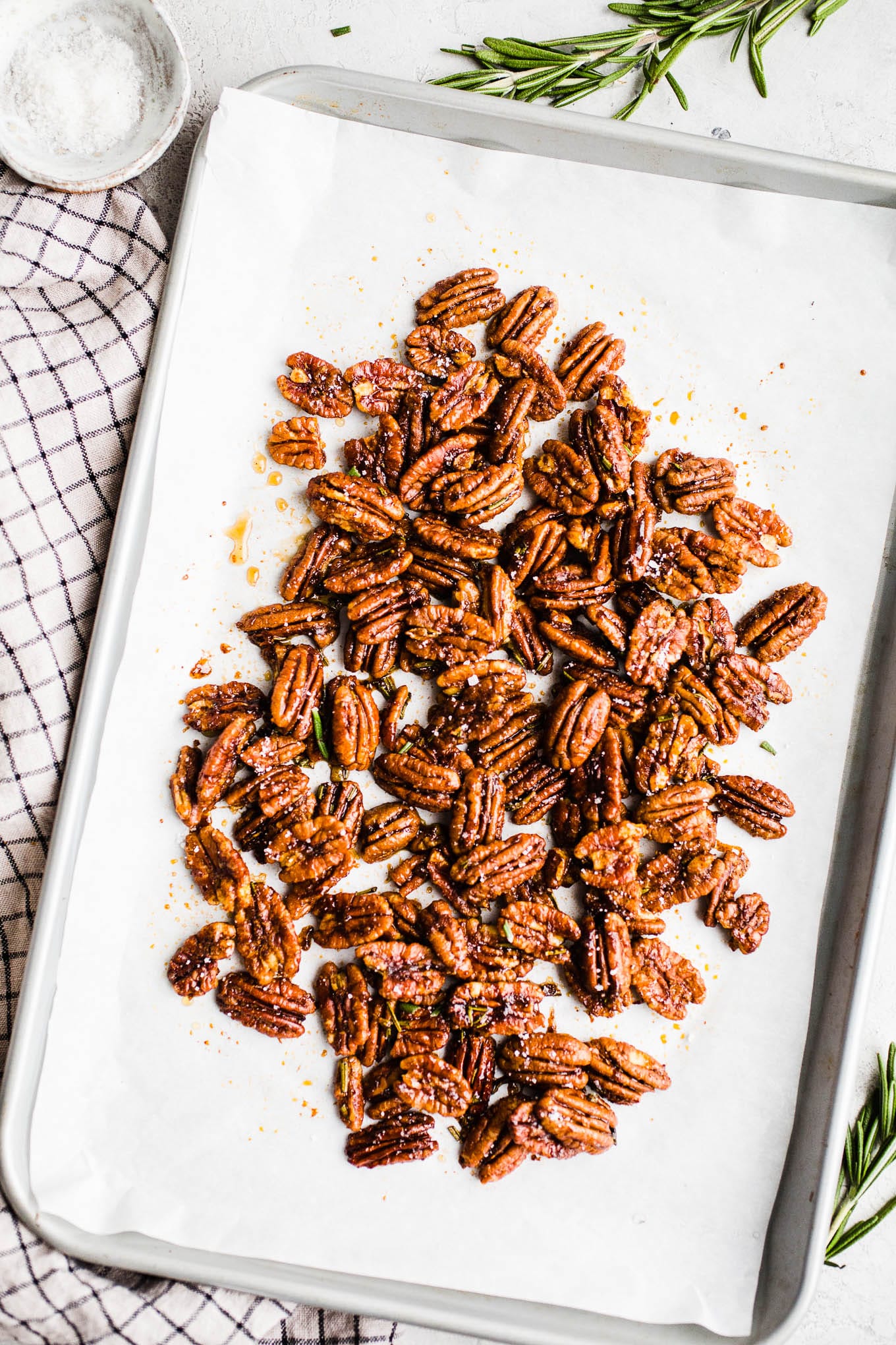 Pecans with maple and rosemary on a baking sheet. 