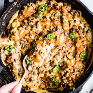 Cheesy black bean dip with jalapenos in a cast iron skillet.