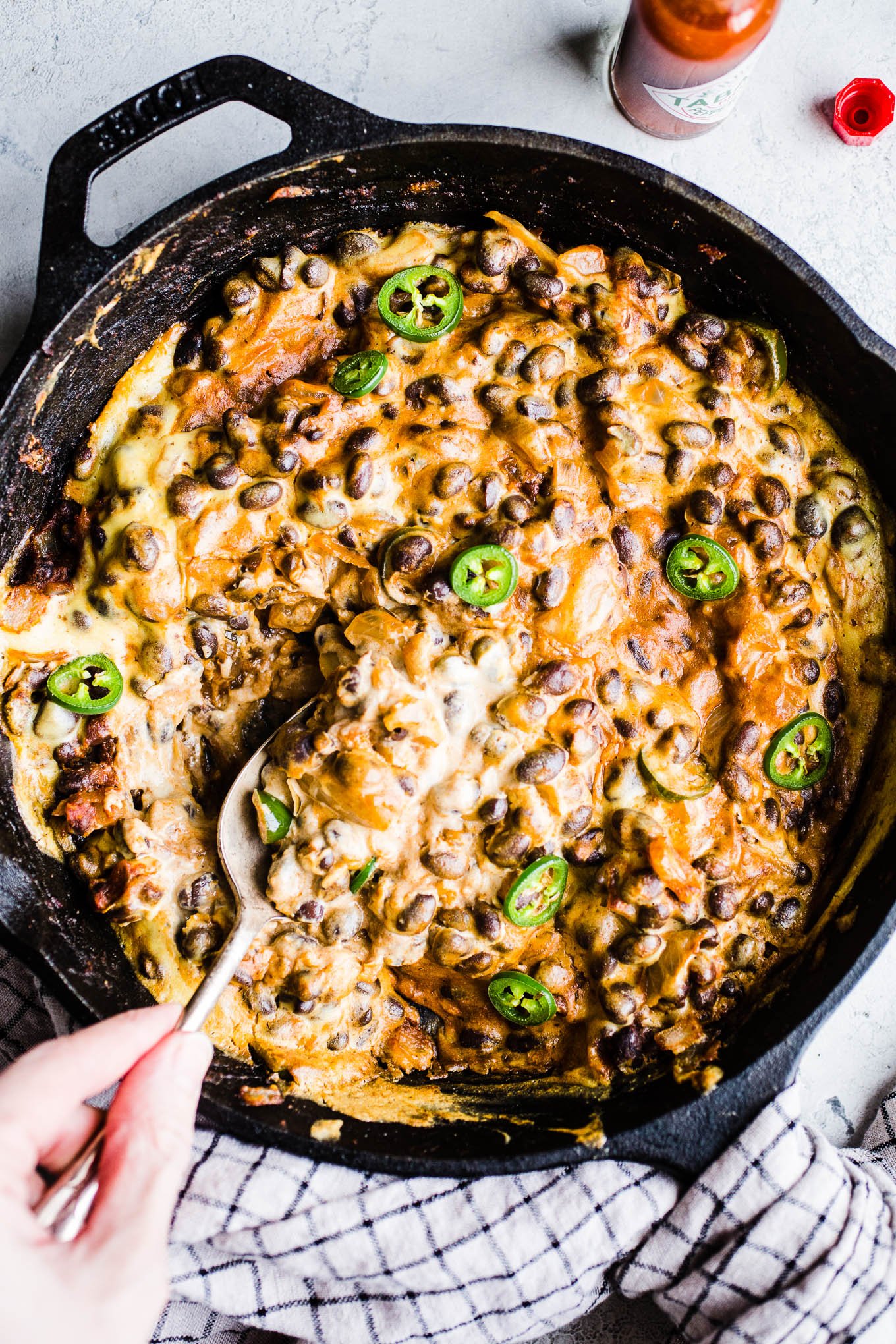 Cheesy black bean dip with jalapenos in a cast iron skillet.