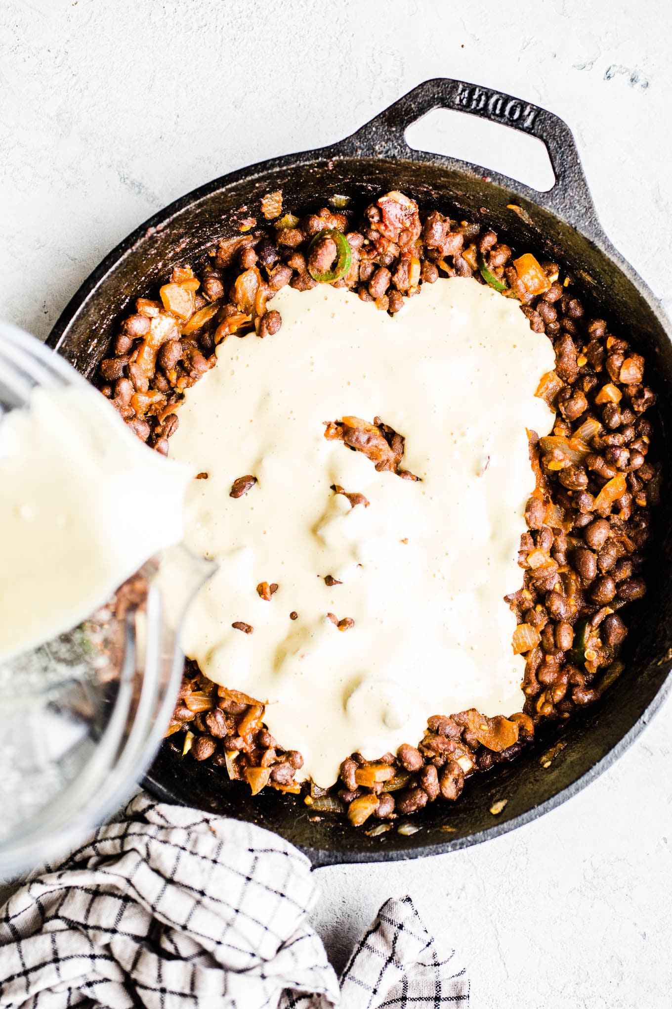 Cashew cheese and cooked black beans in a skillet. 