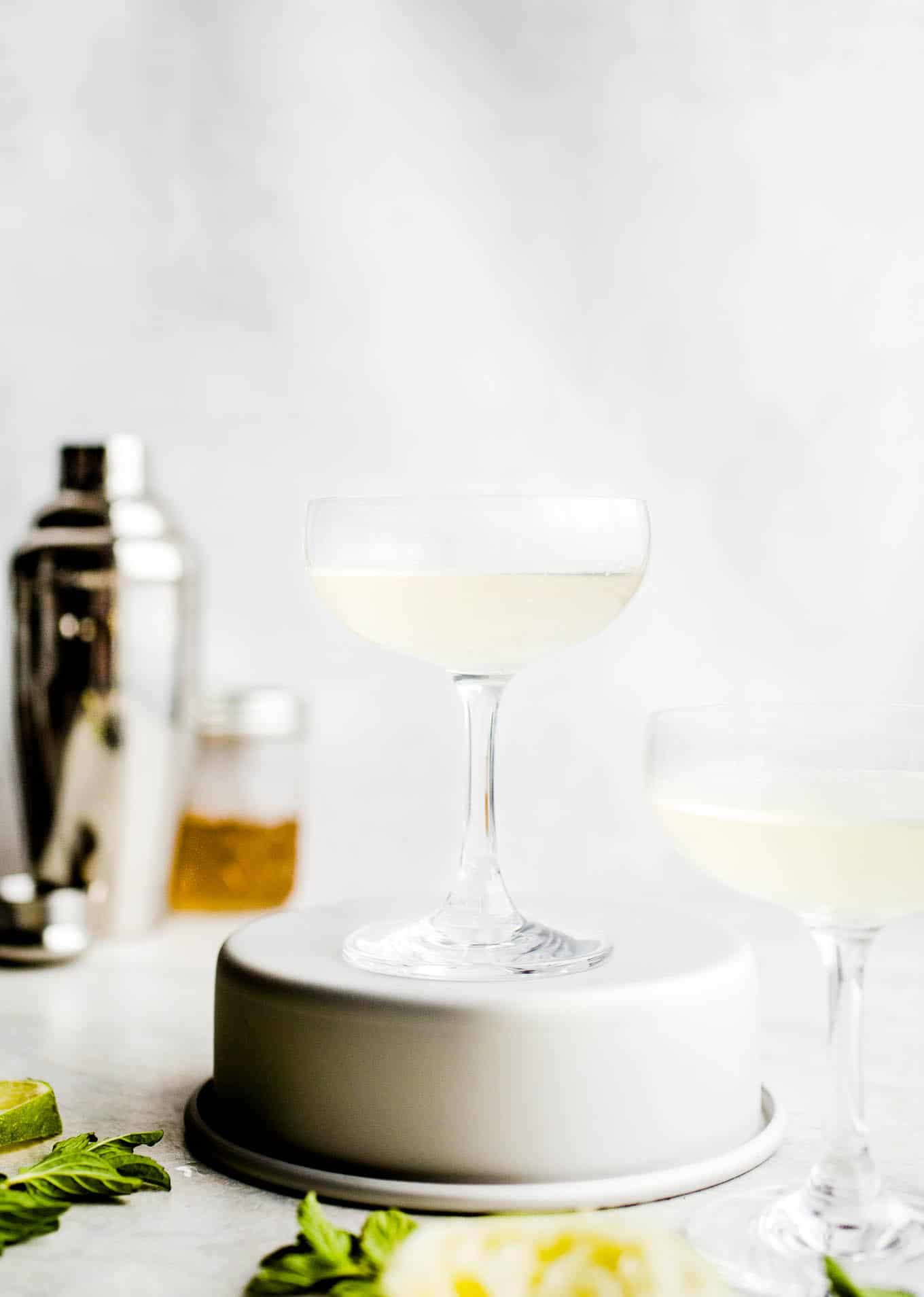 A gimlet in a coupe glass set on a silver stand. 