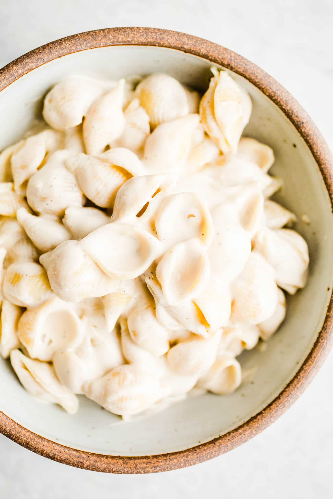 Pasta with alfredo sauce in a rustic bowl.