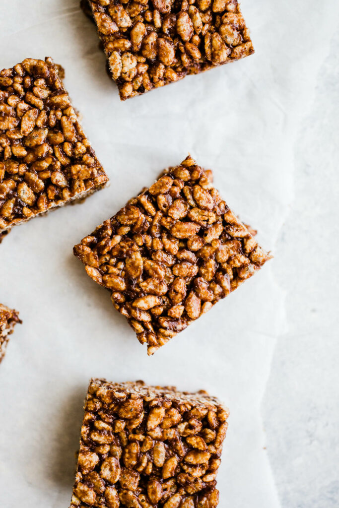 Chocolate squares made with rice cereal on parchment paper.