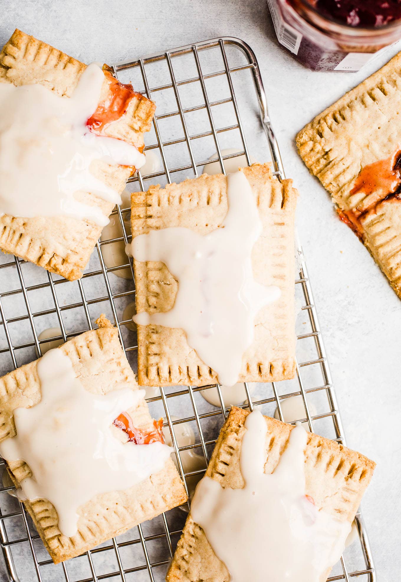 Glazed toaster pastries with jam on a cooling rack.