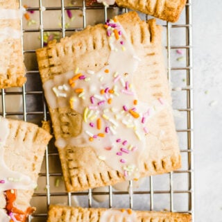 Glazed toaster pastries with sprinkles on a wire rack.