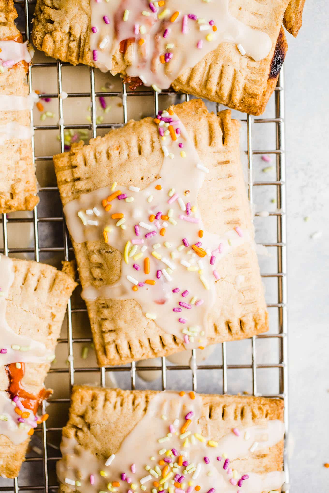 Glazed toaster pastries with sprinkles on a wire rack.