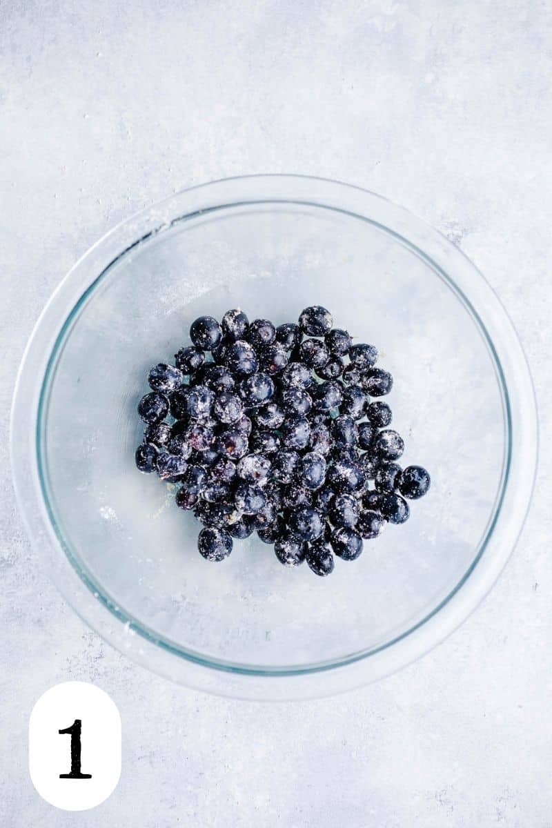 Blueberries coated in oat flour in a glass bowl.