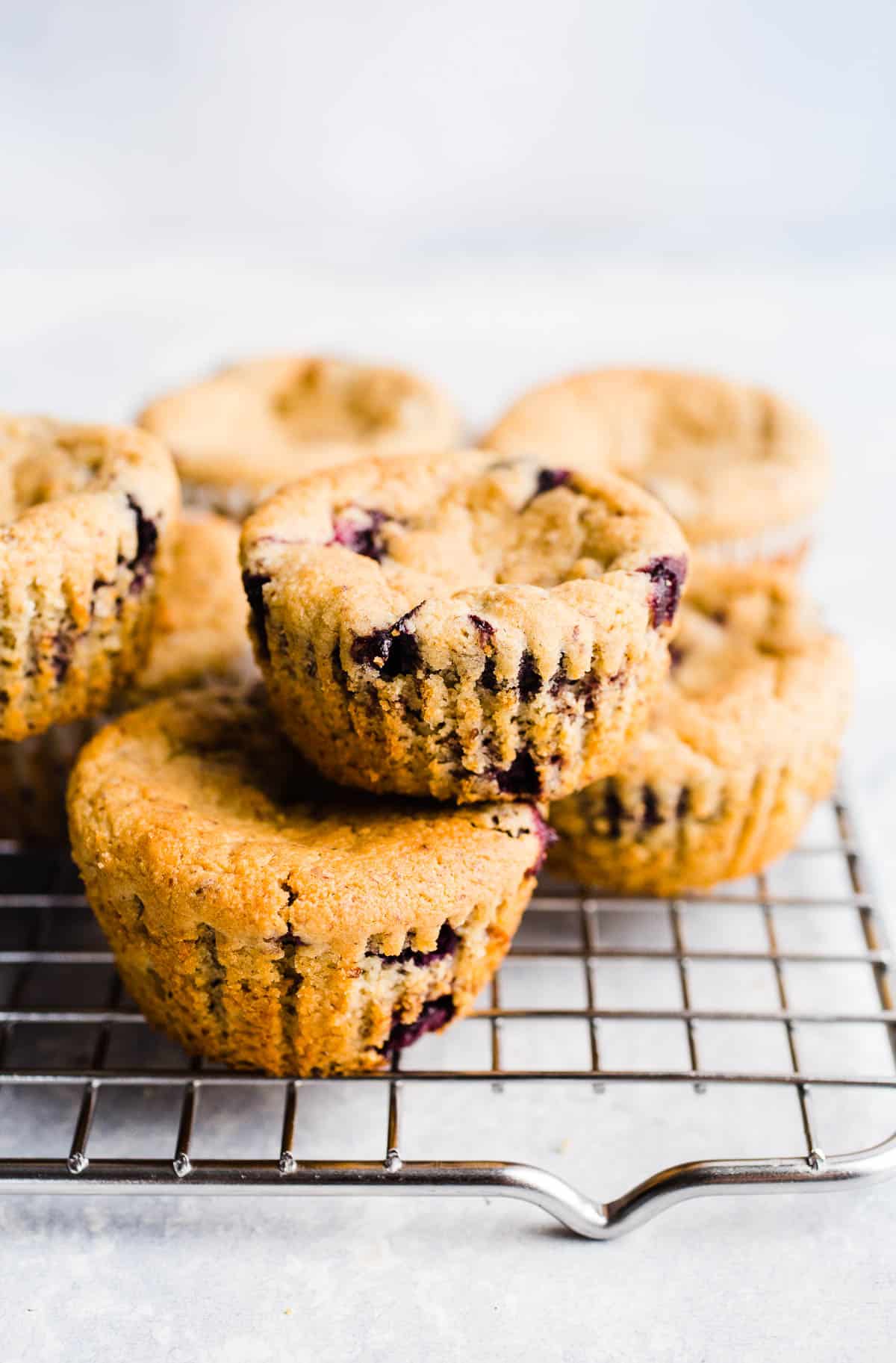 Blueberry muffins stacked two by two on a wire rack.