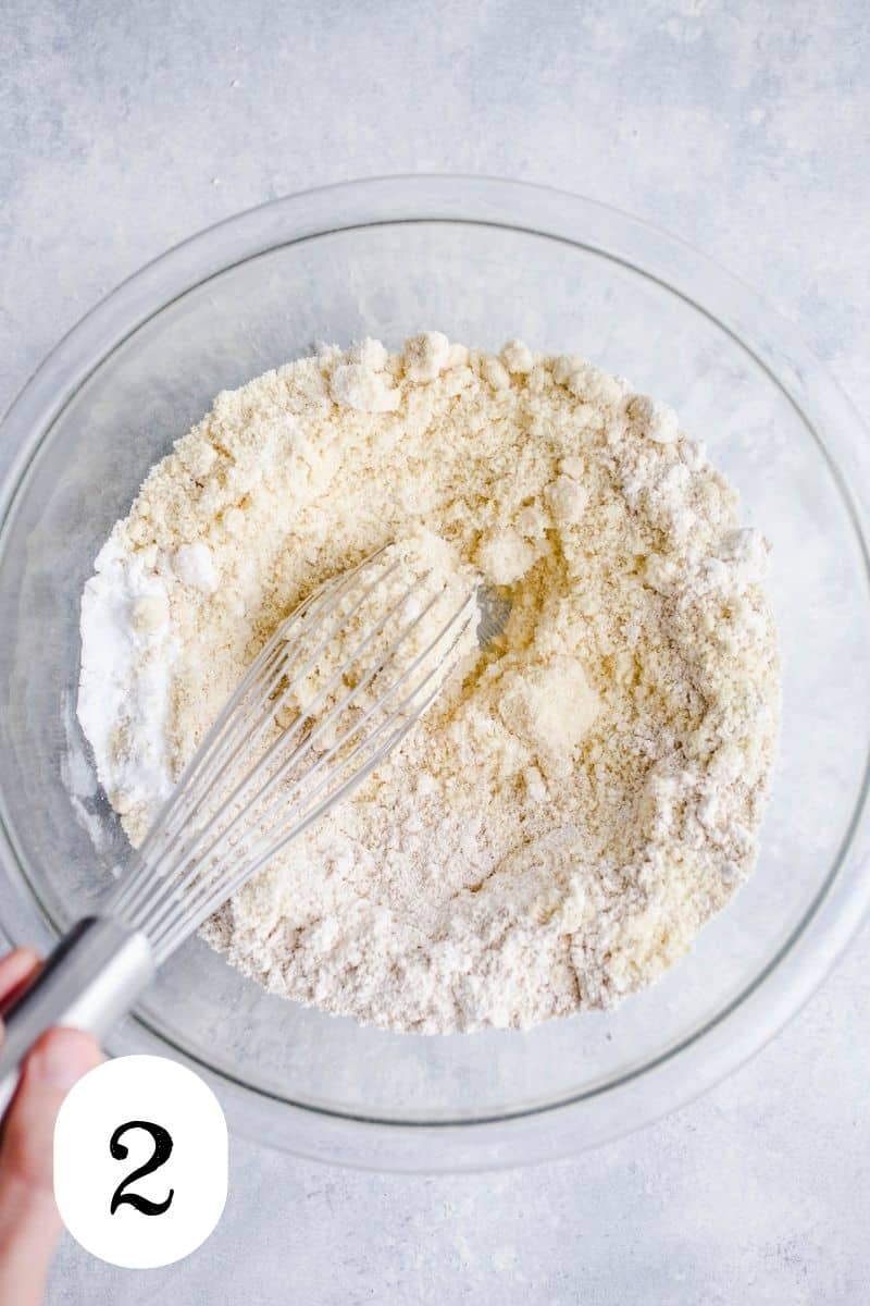 Oat flour, almond flour, salt, and baking powder being whisked in a glass bowl. 