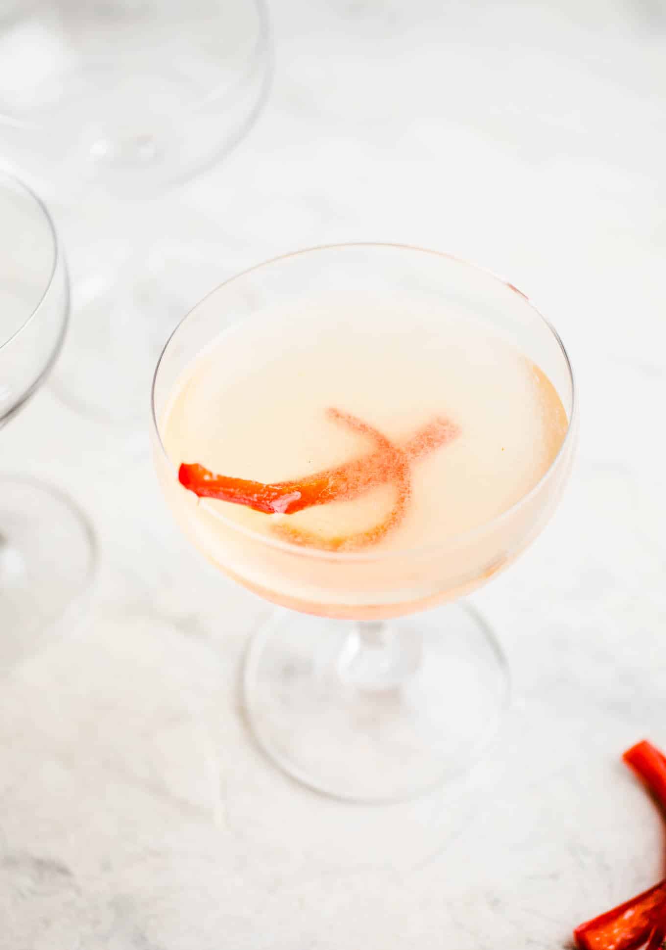 A coupe glass with red pepper cocktail.