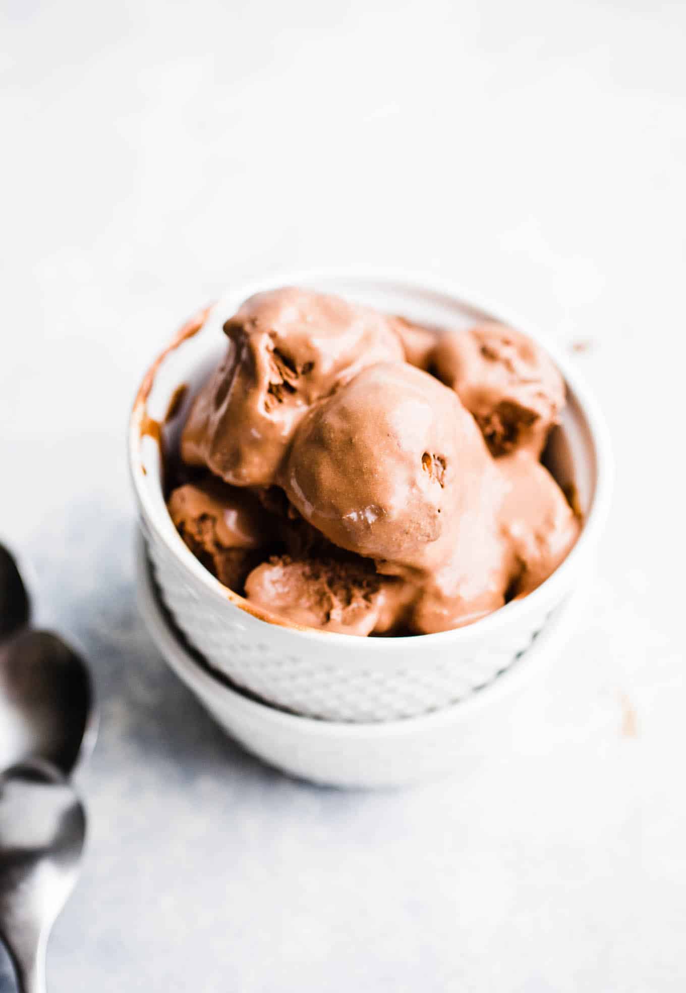 Scoops of chocolate ice cream in a white bowl.