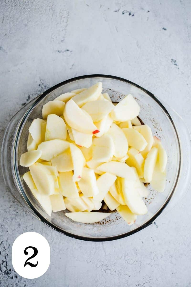 Raw peeled apple slices in a glass bowl.