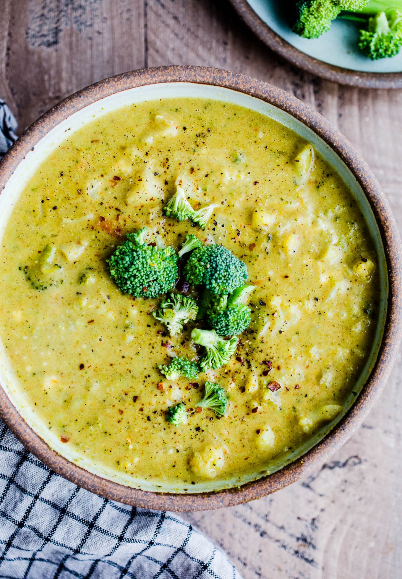 Curried cauliflower soup with broccoli in a rustic bowl on a wooden surface.