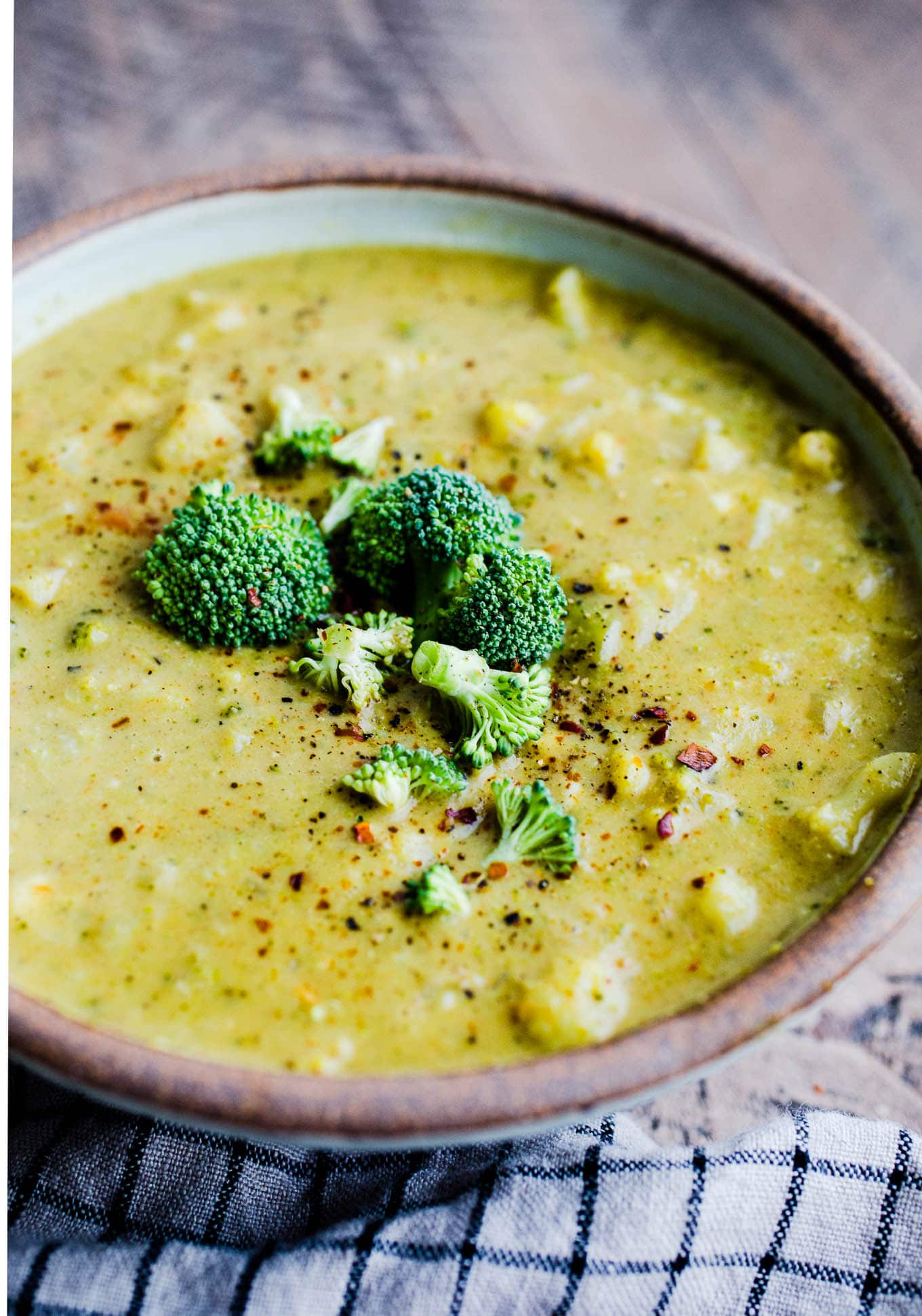 Curried cauliflower soup in a rustic bowl with broccoli on top.