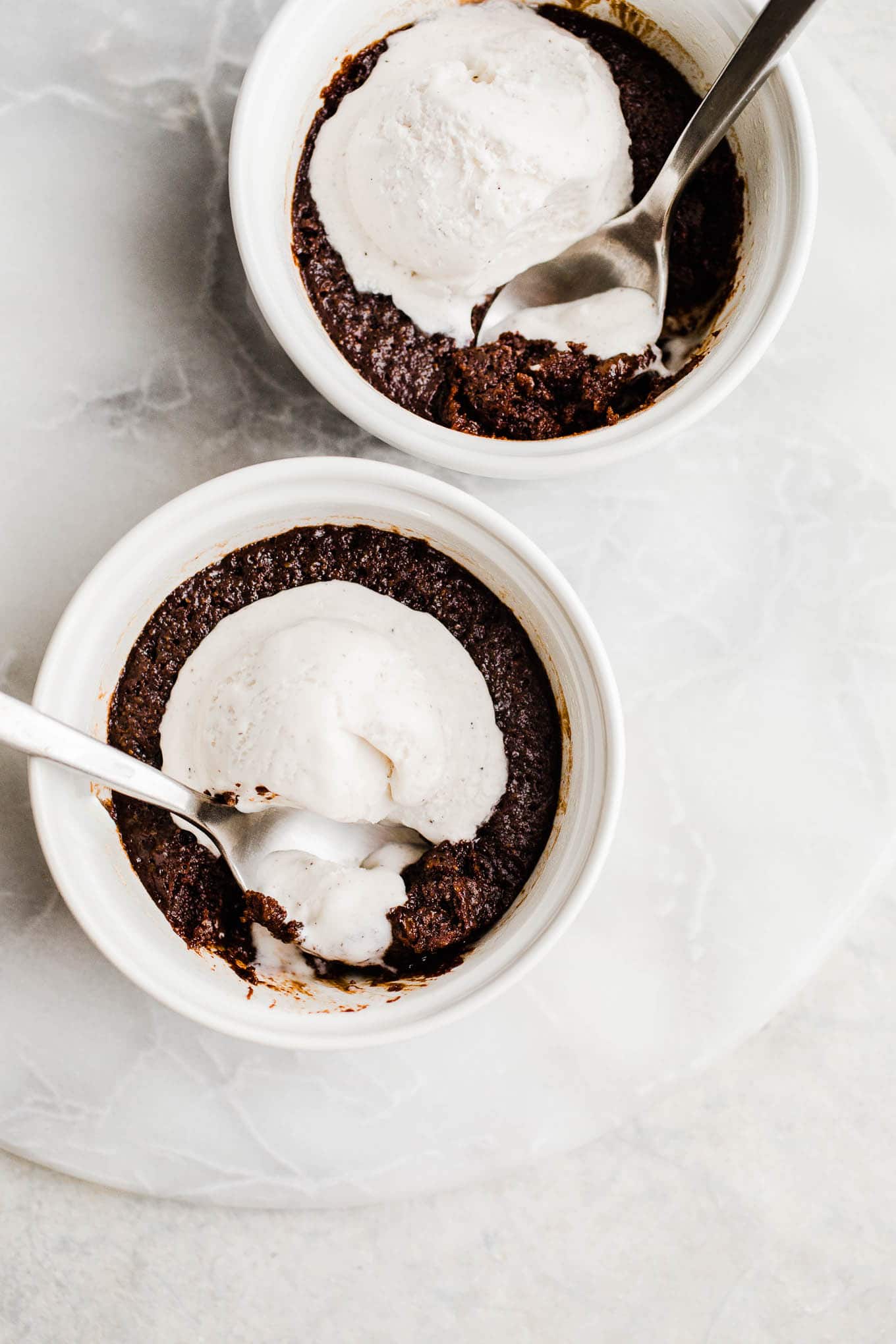 Chocolate cakes with melting ice cream in ramekins.