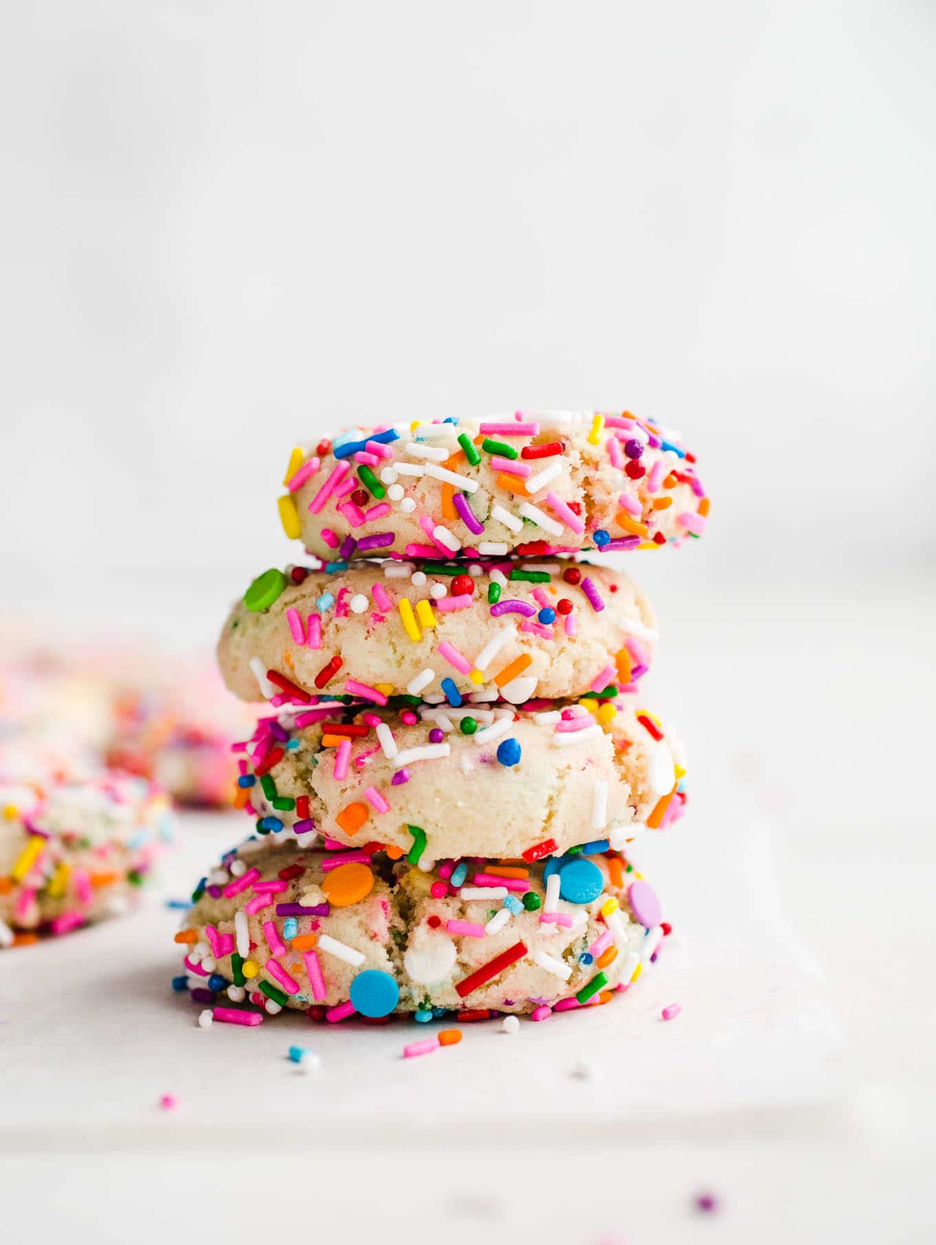 cookies with sprinkles stacked on parchment paper