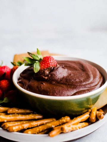 Chocolate hummus on a platter with fruit and pretzels.