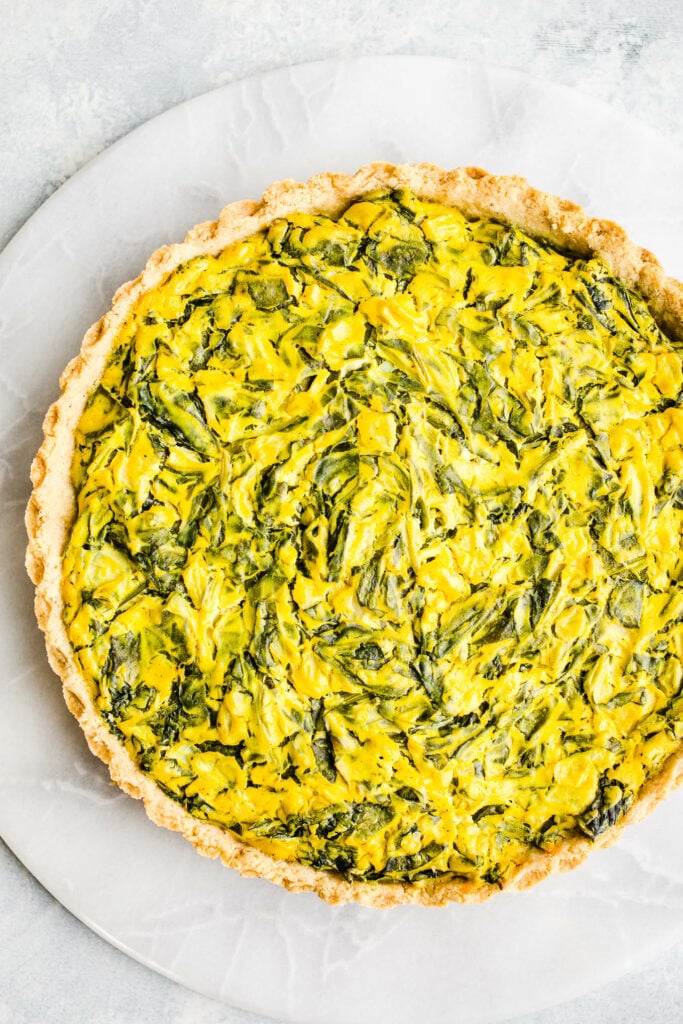 Tofu quiche with spinach on a marble surface.