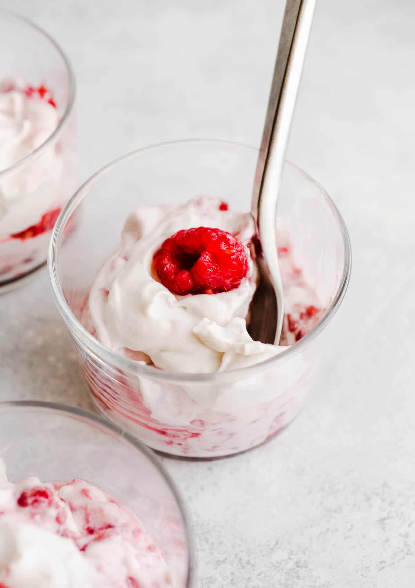 Coconut whipped cream and fresh raspberries in cup