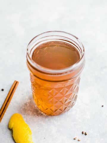 A golden-colored syrup in a small glass jar.