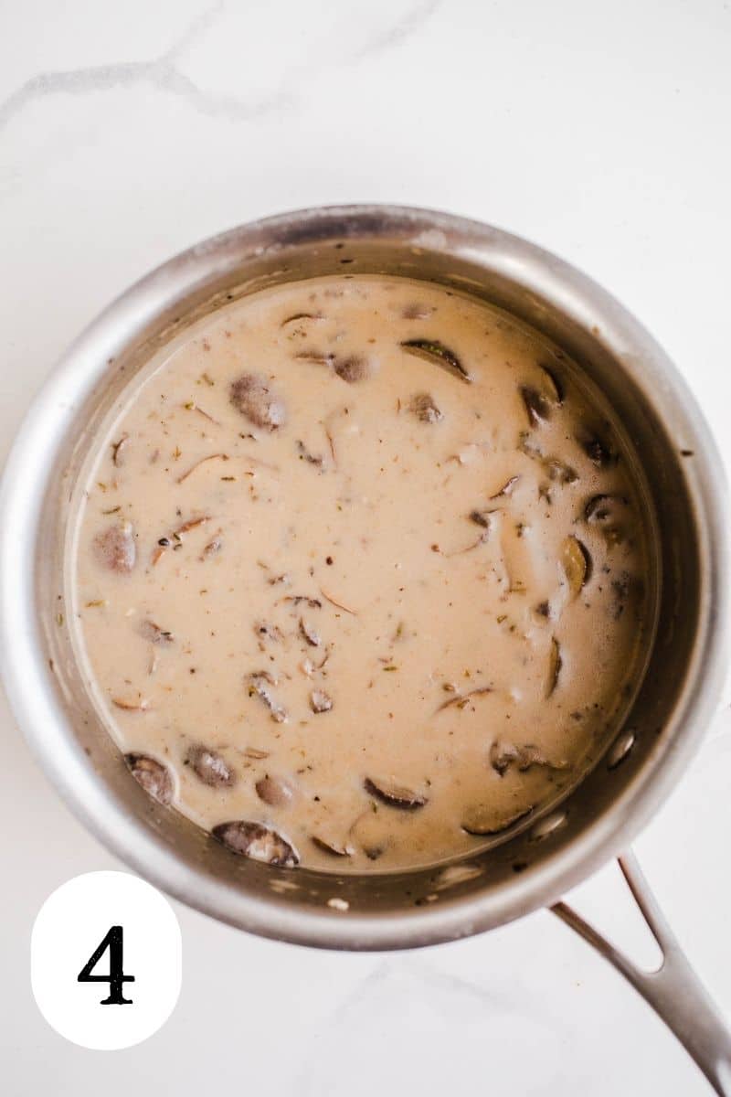 Simmered cream of mushroom soup in a stainless steel saucepan.