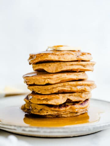 A stack of pancakes dripping with syrup on a plate.
