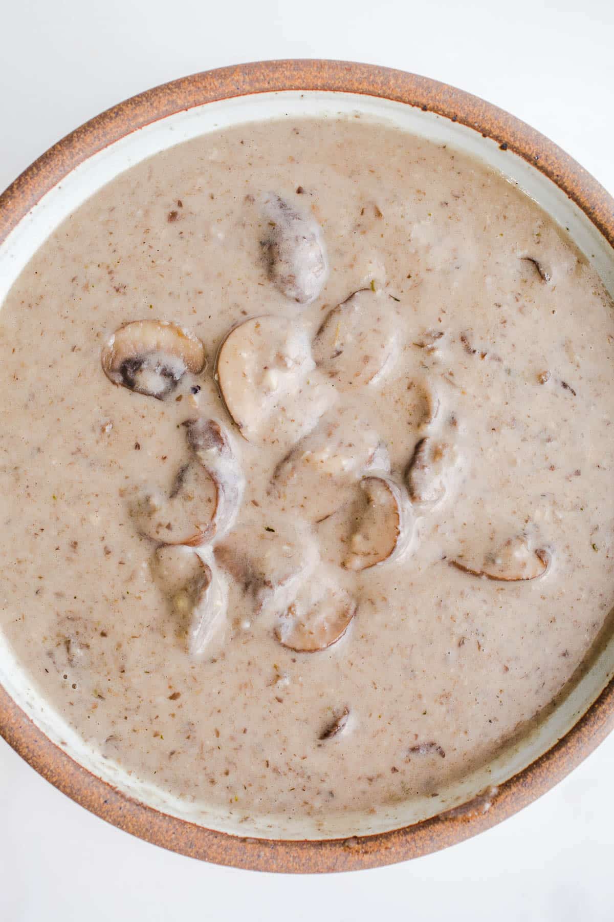 Creamy mushroom soup in a rustic bowl on a marble surface.