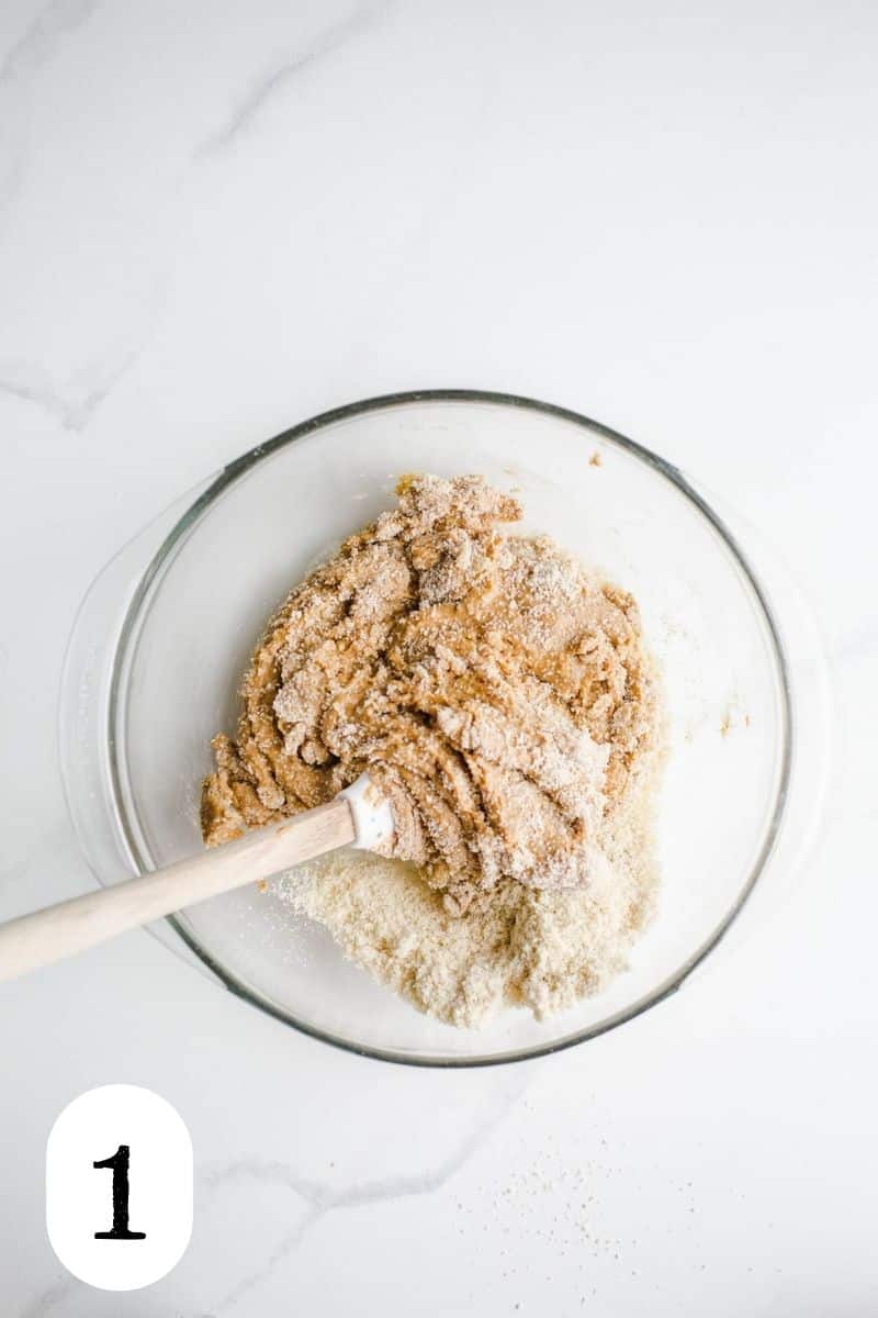 Almond flour and peanut butter being mixed in a glass bowl.