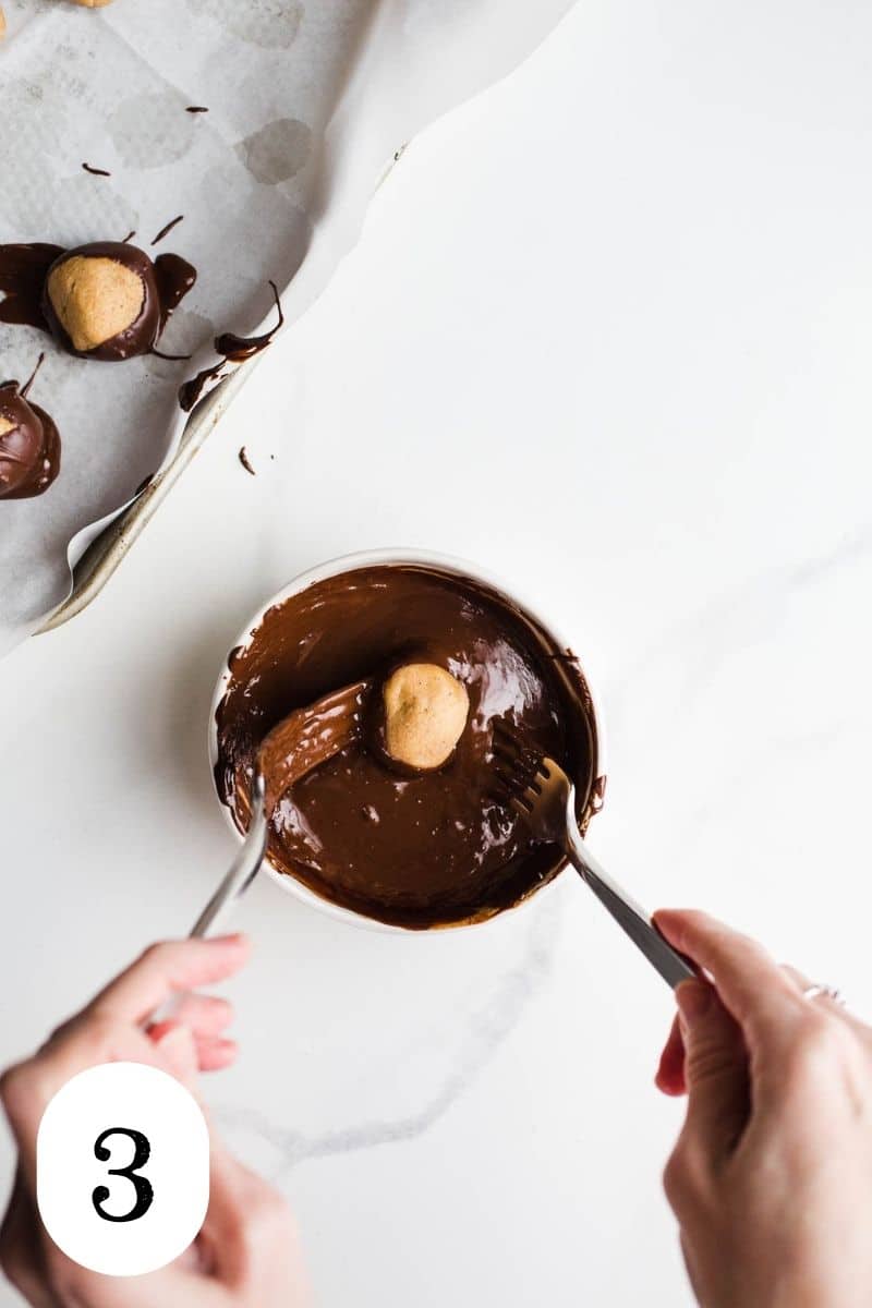 A peanut butter ball being dipped in melted chocolate.