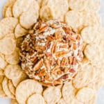 A cheese ball with pecans surrounded by crackers.