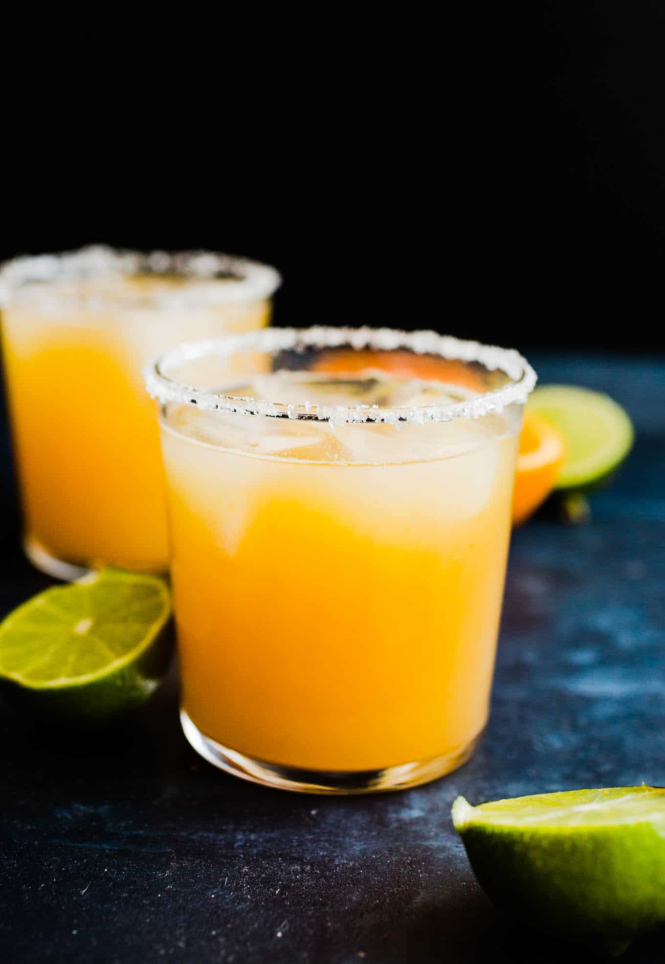 two margaritas in glasses with salt and limes