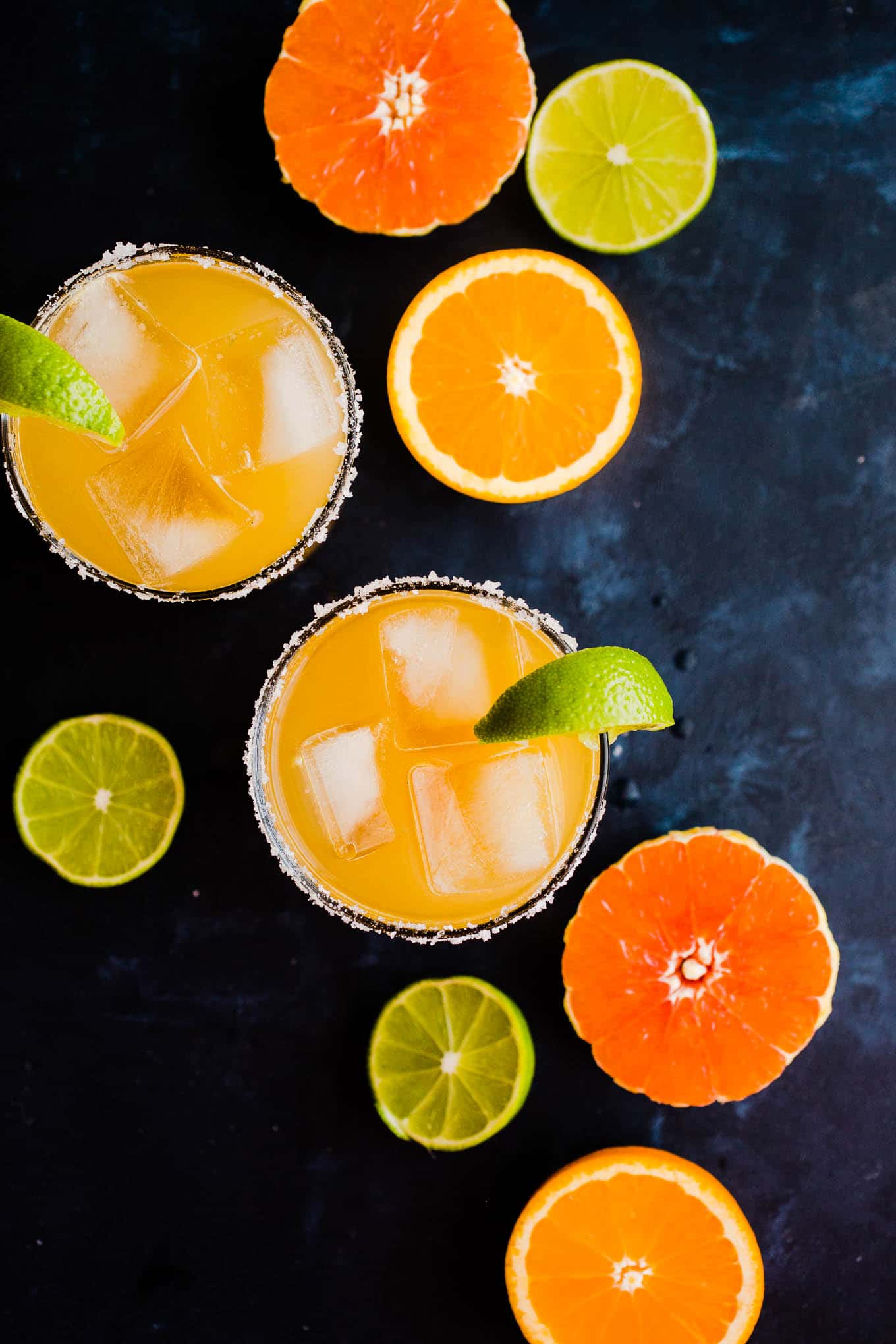 two citrus margaritas with limes, grapefruit, and oranges