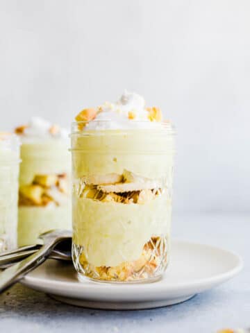 yellow pudding layered with vanilla cookies and banana slices in a glass jar.