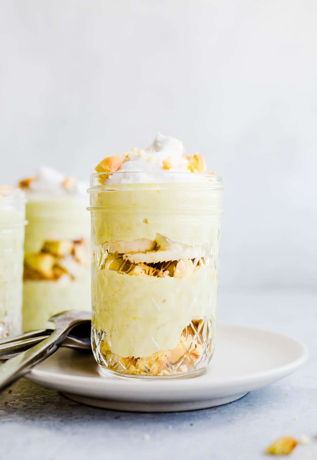 banana pudding, vanilla wafers, and banana slices layered in a glass jar topped with whipped cream.