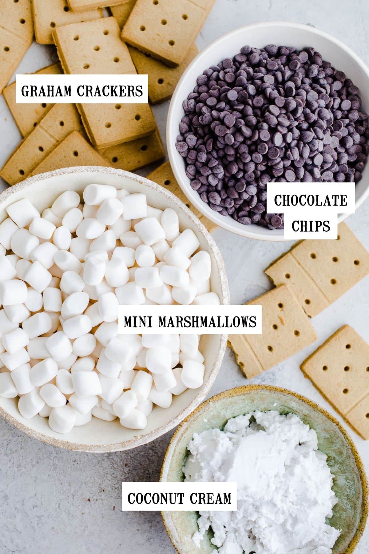 Marshmallows, chocolate chips, graham crackers, and coconut cream in bowls.
