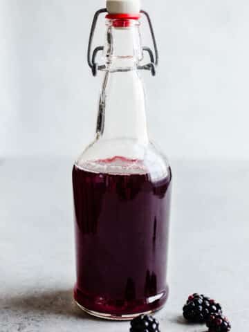 A glass bottle containing blackberry simple syrup with the lid sealed closed.