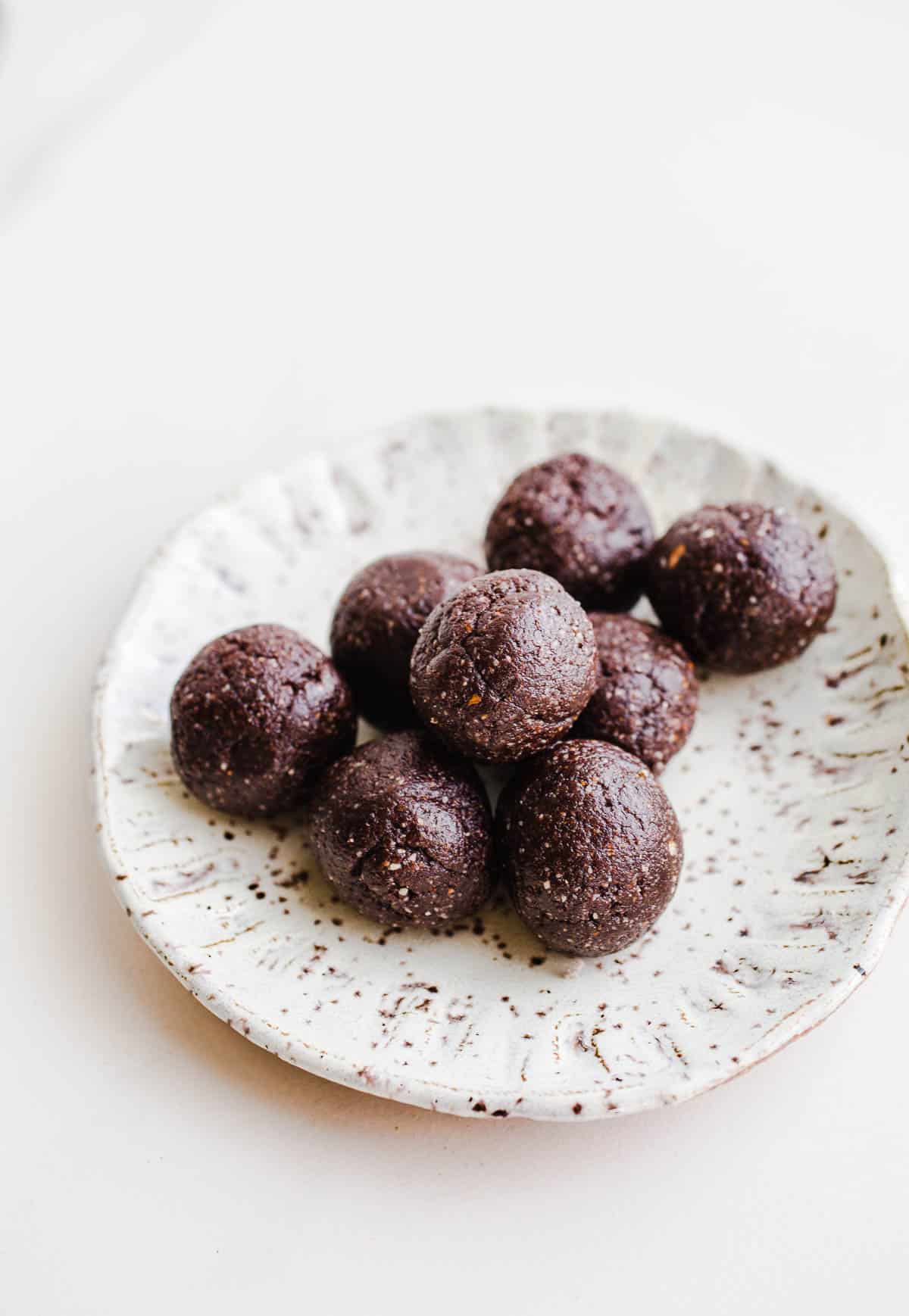 Eight date energy balls on a small speckled plate.