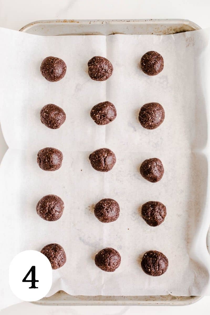 Date balls lined in even rows on a parchment paper lined baking sheet.