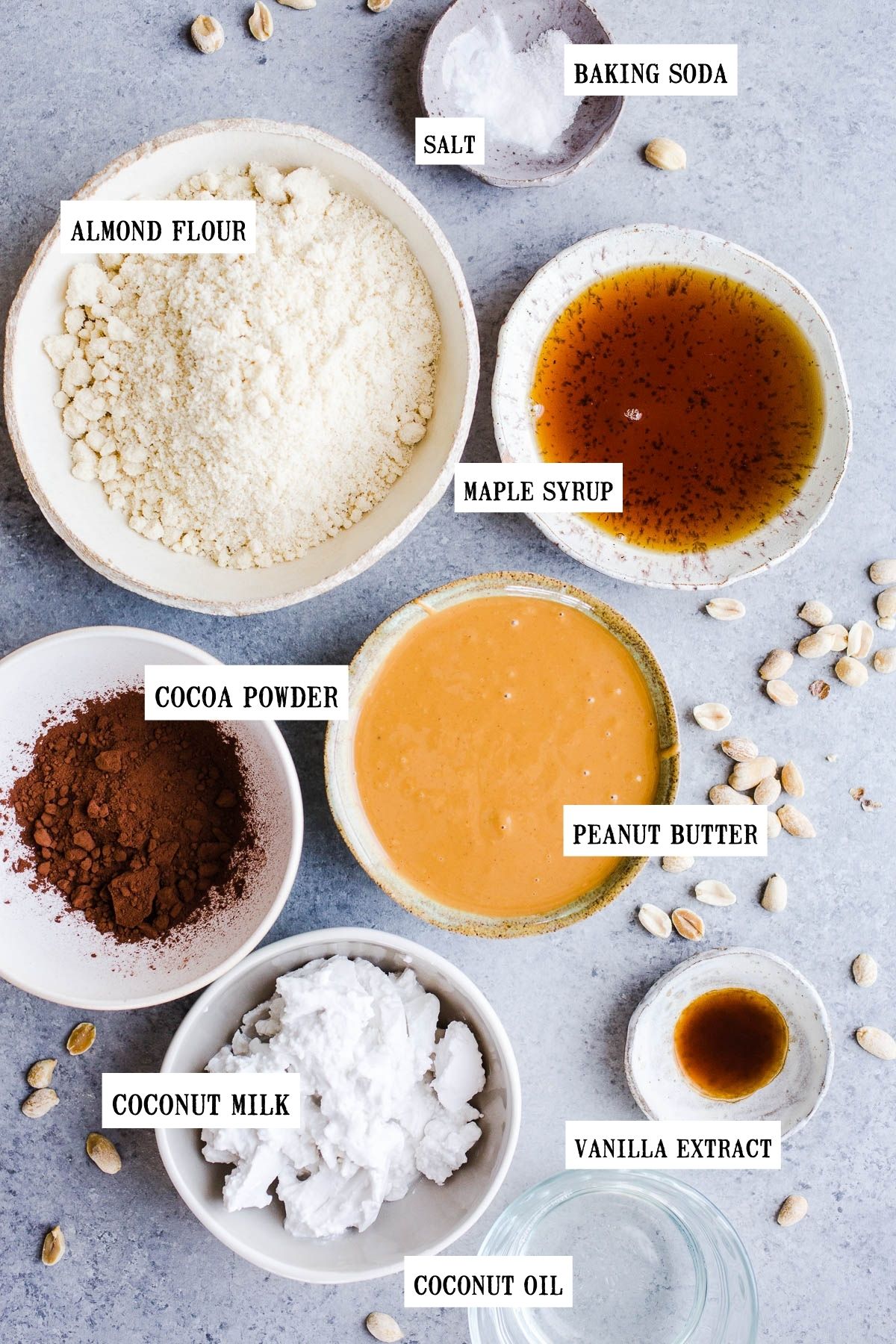 Ingredients for peanut butter pie in small ceramic bowls on a gray surface.