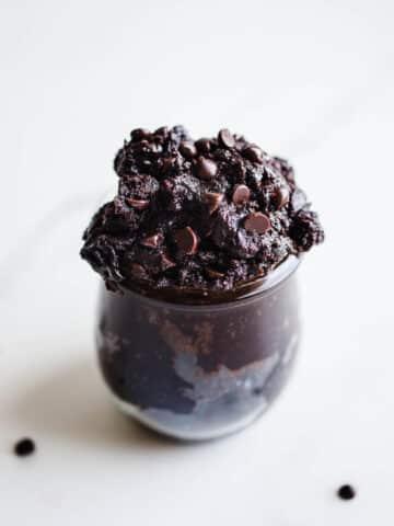 Brownie batter with chocolate chips in a small glass jar.