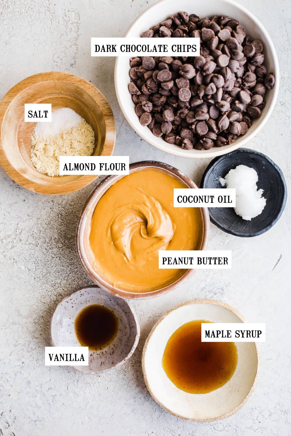 Ingredients for peanut butter cups in small bowls on a gray surface.
