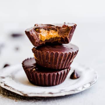 Three peanut butter cups stacked on top of each other on a mini white plate.
