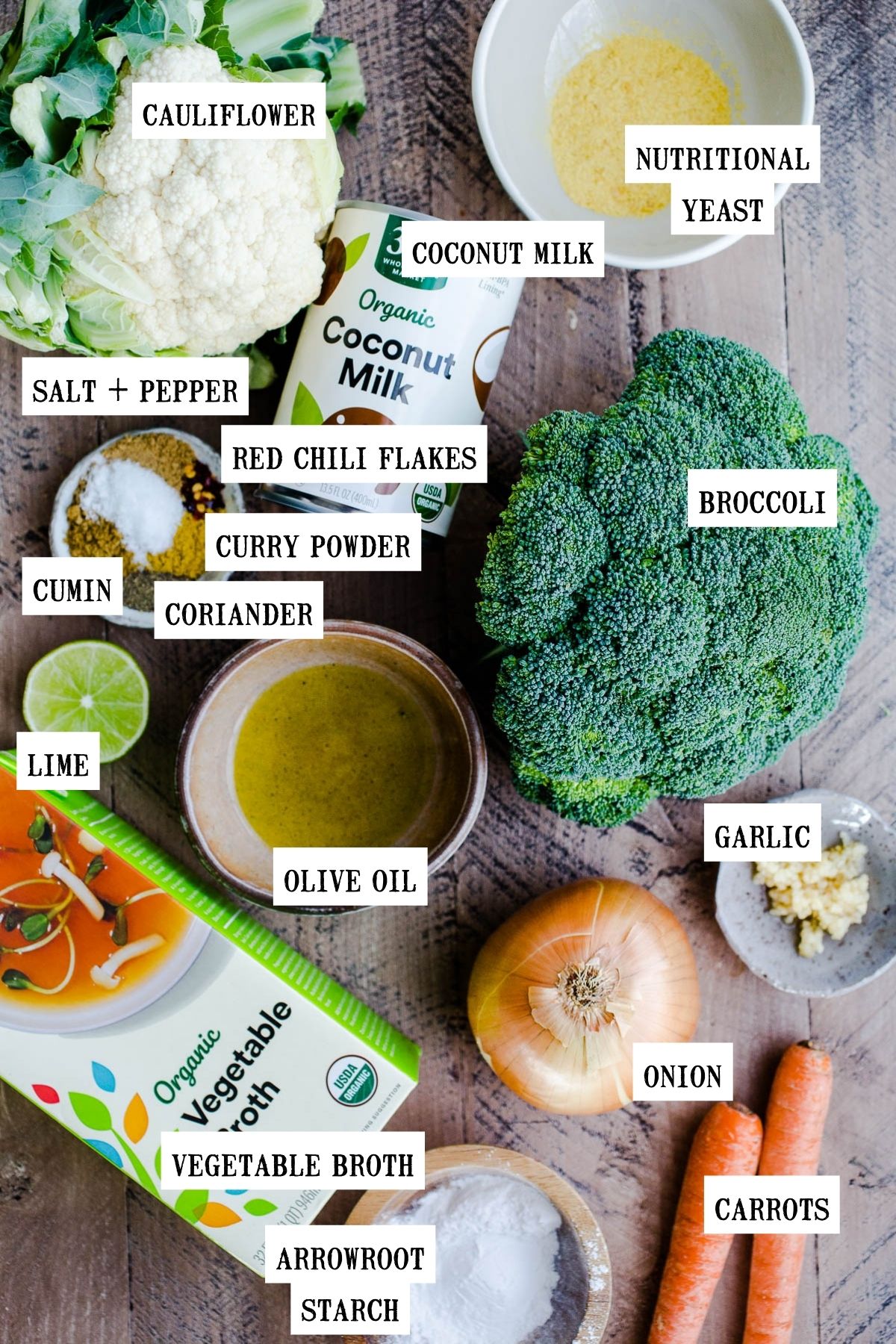 Ingredients for broccoli cauliflower soup laid out on a wooden surface.