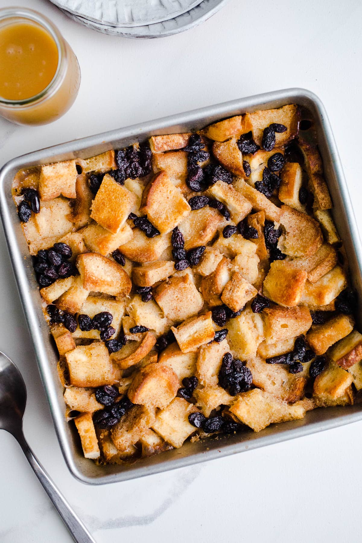 Bread pudding with raisins in a square baking pan.