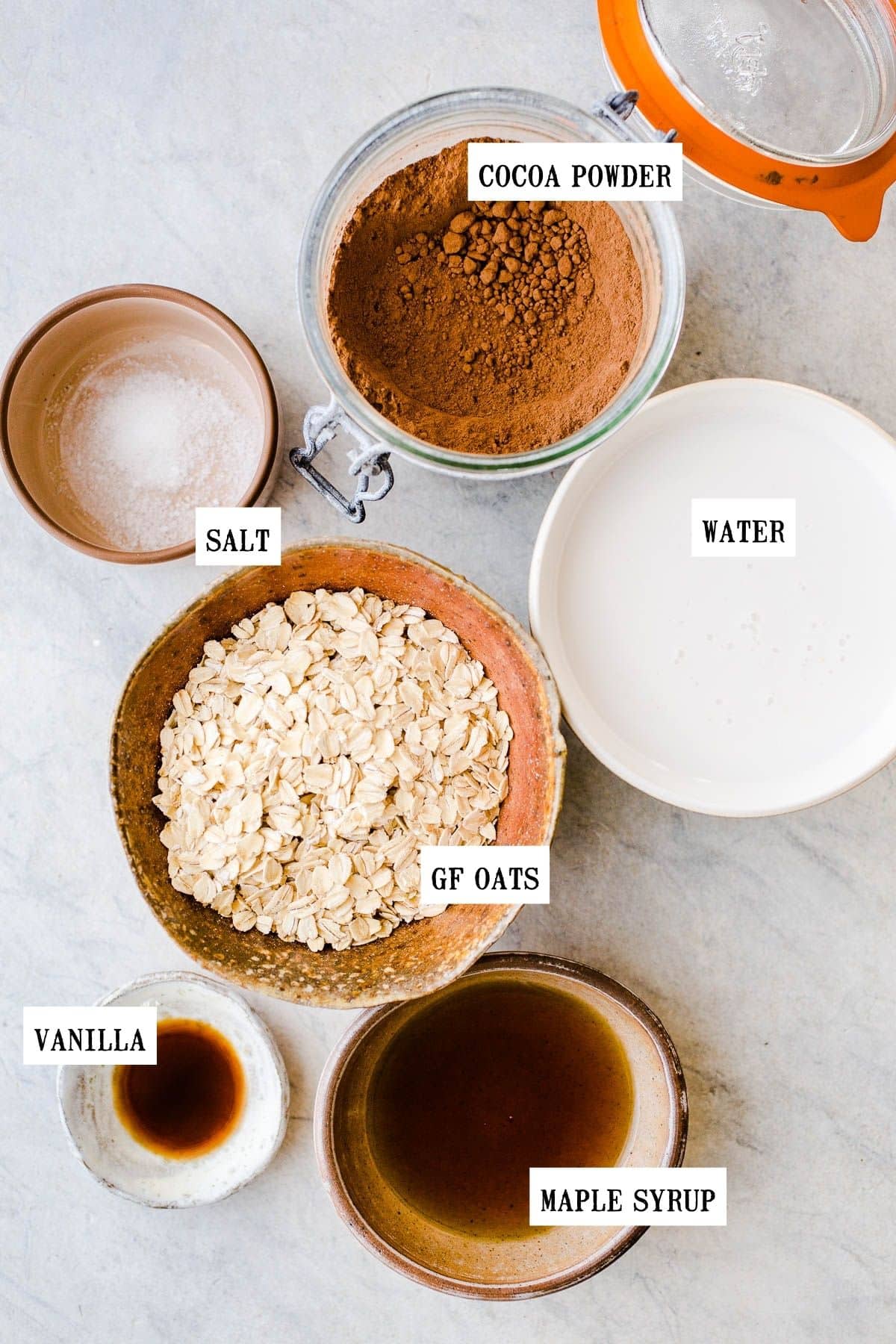 Ingredients to make chocolate oatmeal in small and medium bowls.