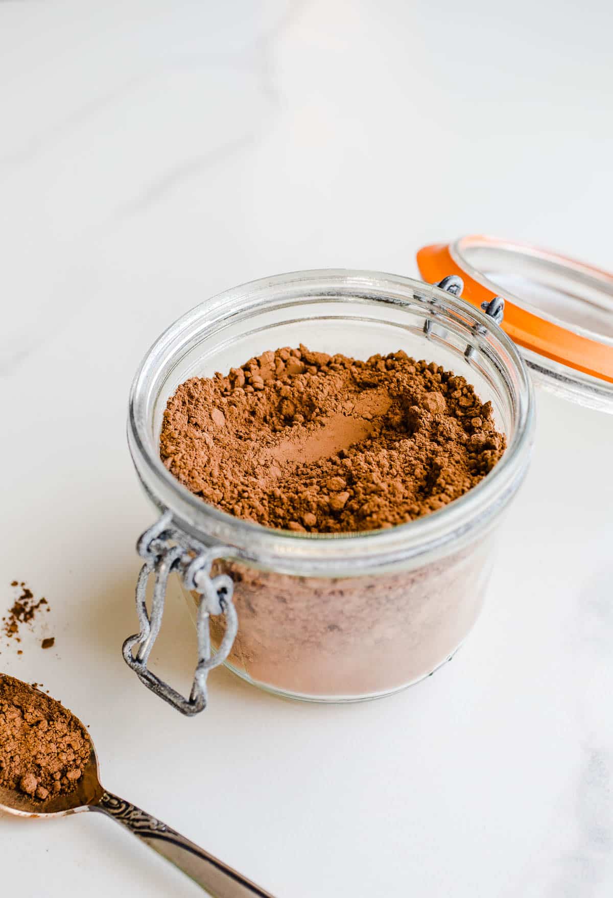 An open glass canister filled with cocoa powder.