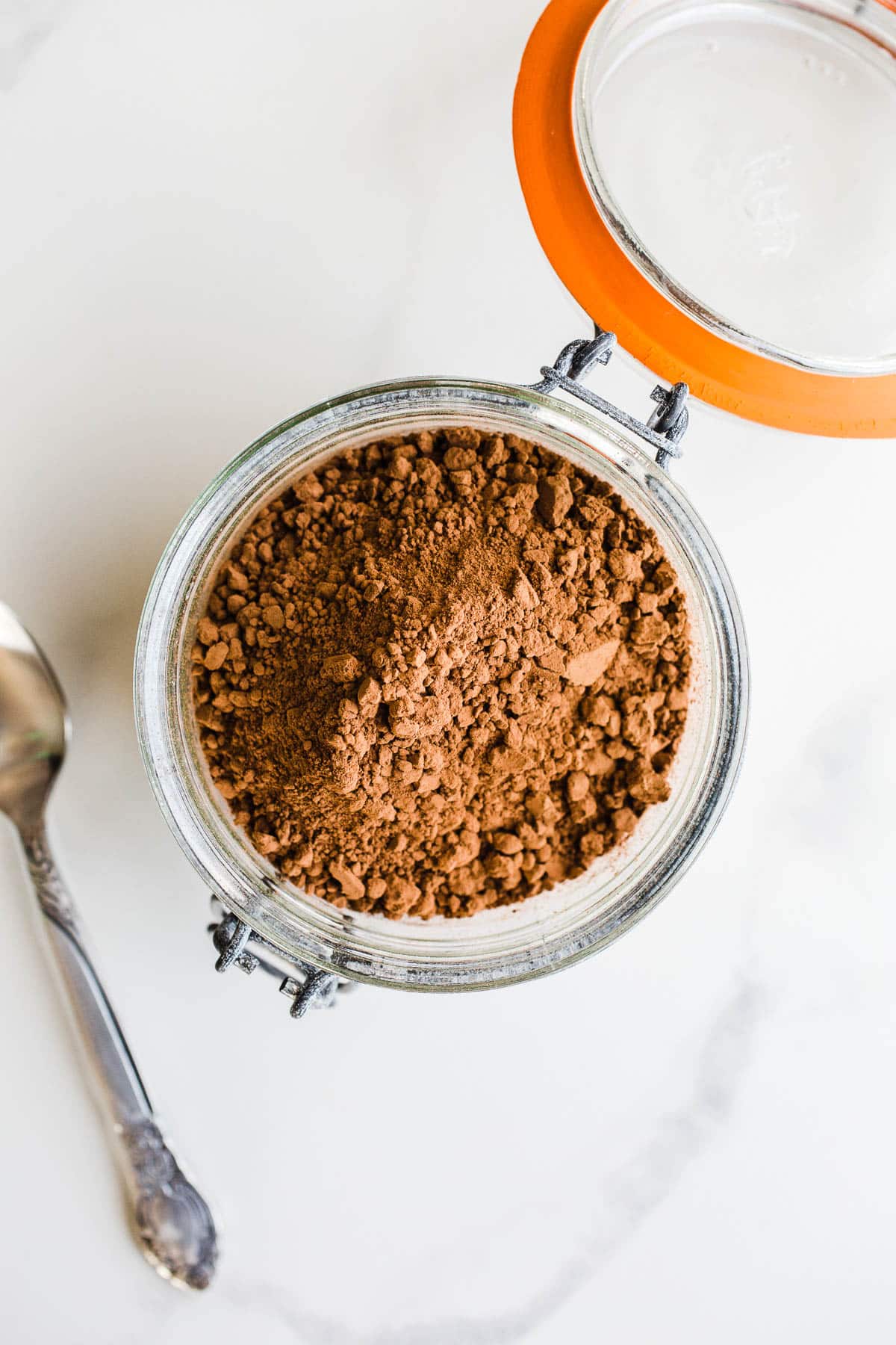 A glass canister of unsweetened cocoa powder.